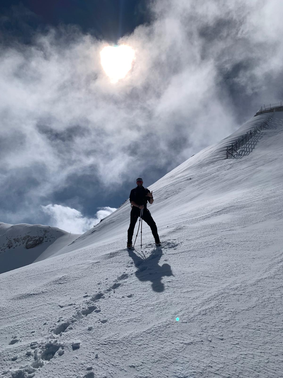 Jakob ascending a snow slope with trekking poles
