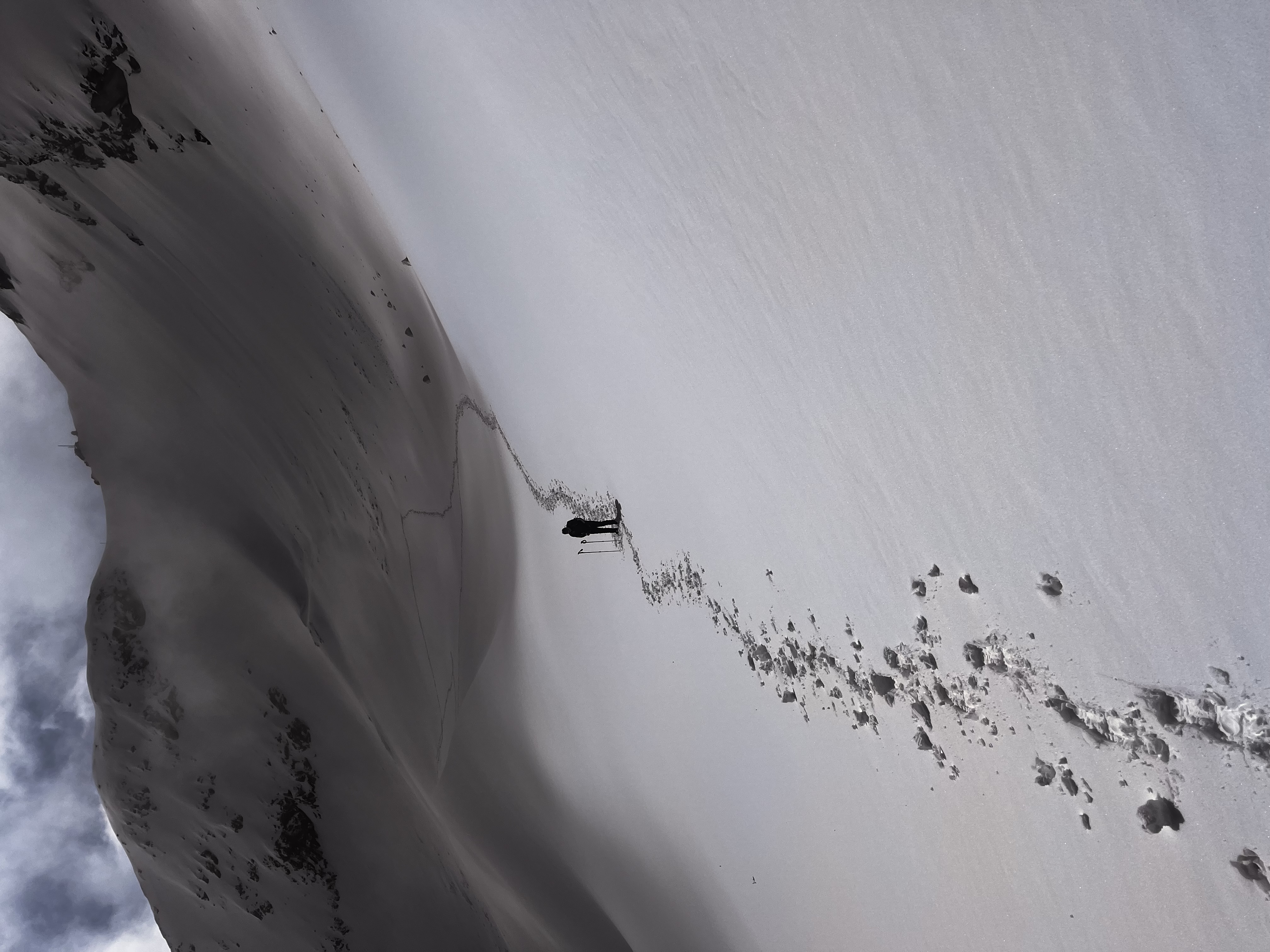 A lone climber - barely a dot - on a vast alpine face