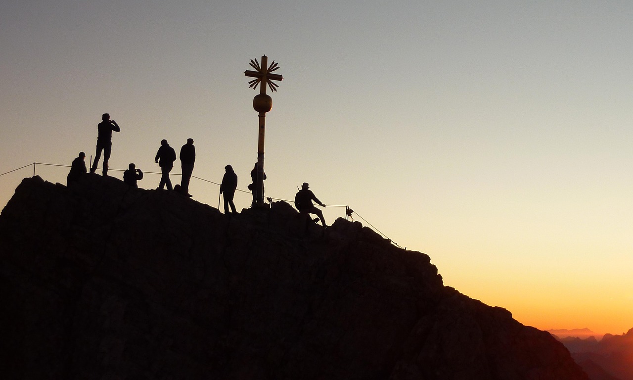 A climber pausing at a windswept ridge in the pre-dawn light